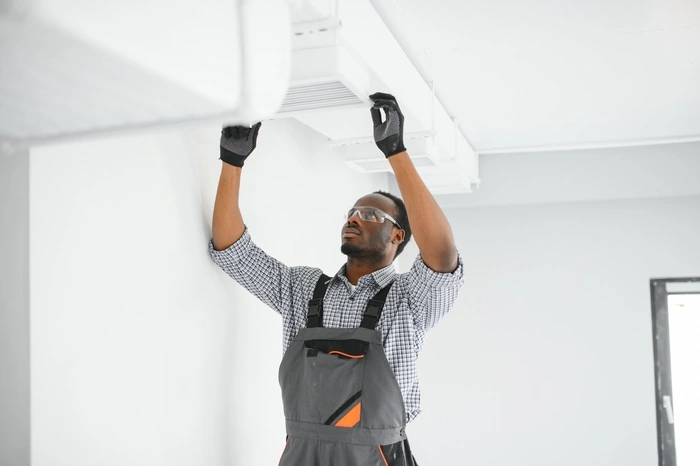 African HVAC Technician Worker Testing Newly Installed Ventilation System.