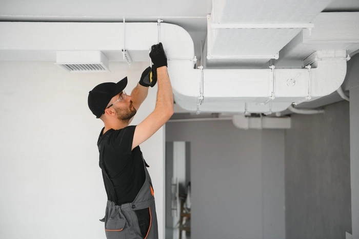 African HVAC Technician Worker Testing Newly Installed Ventilation System.