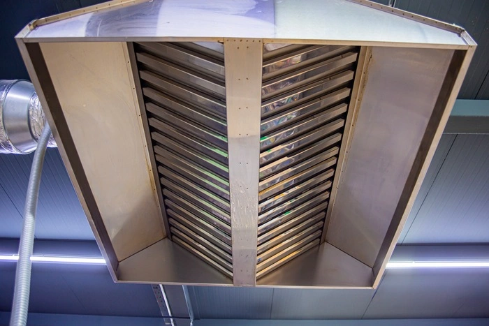 Stainless steel exhaust hood with grease trap close-up in a large industrial kitchen in the production of semi-finished products